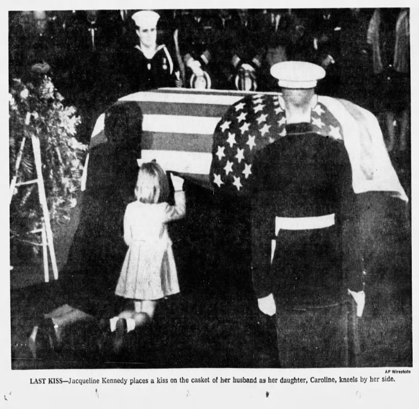 Jacqueline Kennedy, widow of JFK, kisses his casket; Daughter Caroline kneels by her side