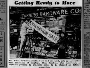 Photo of an American store owner and employee of Japanese descent hanging sale notice